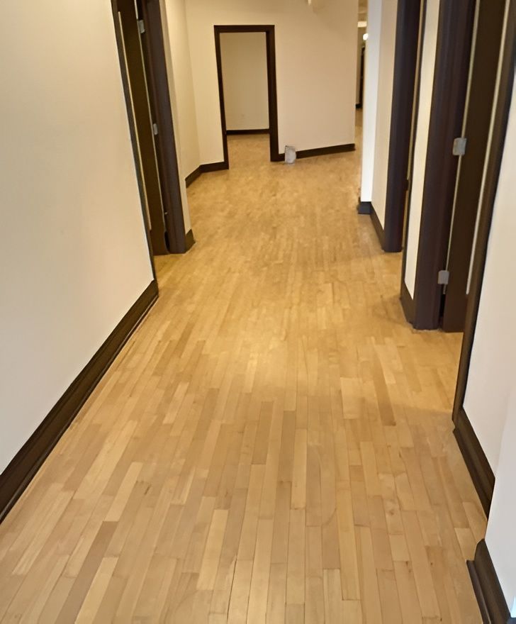 Hallway with light wood floor, white walls, and dark brown door frames.