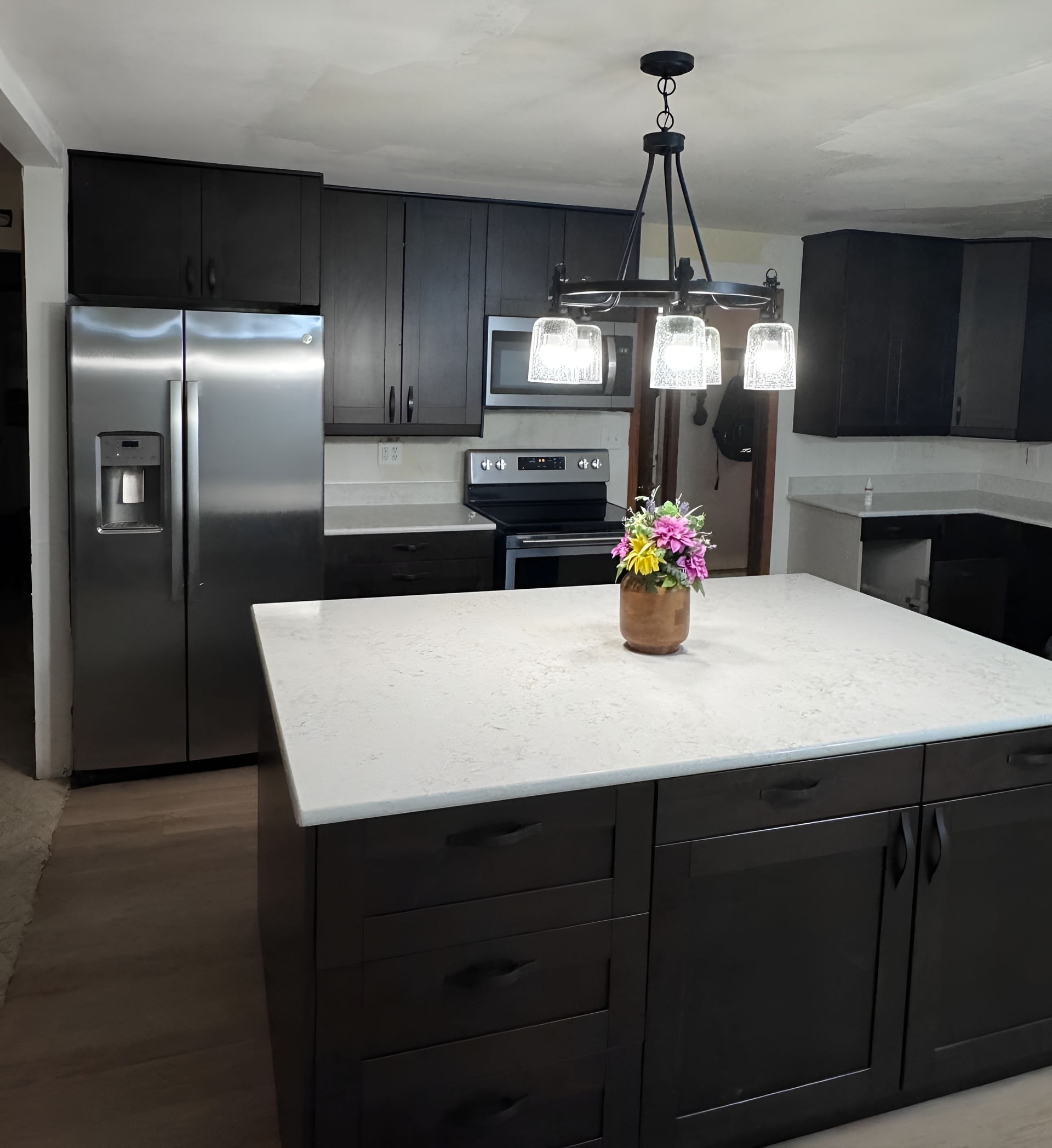 Modern kitchen with dark cabinetry, stainless steel appliances, and a white quartz island countertop.