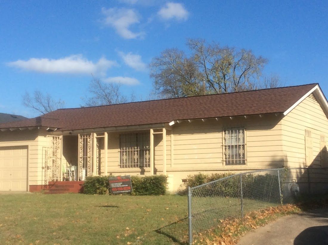 A house with a brown roof and a fence in front of it.