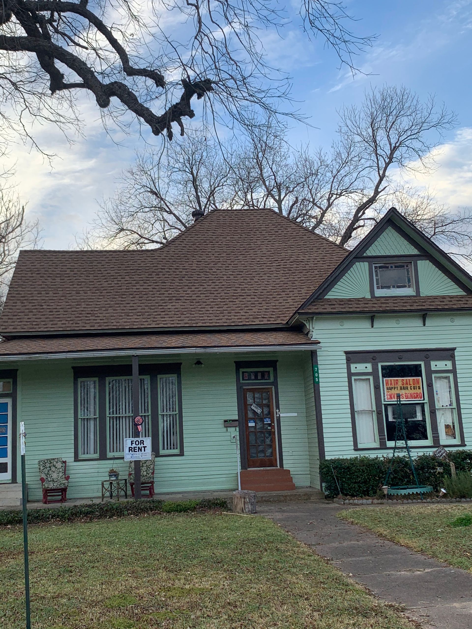 A green house with a brown roof is for sale.