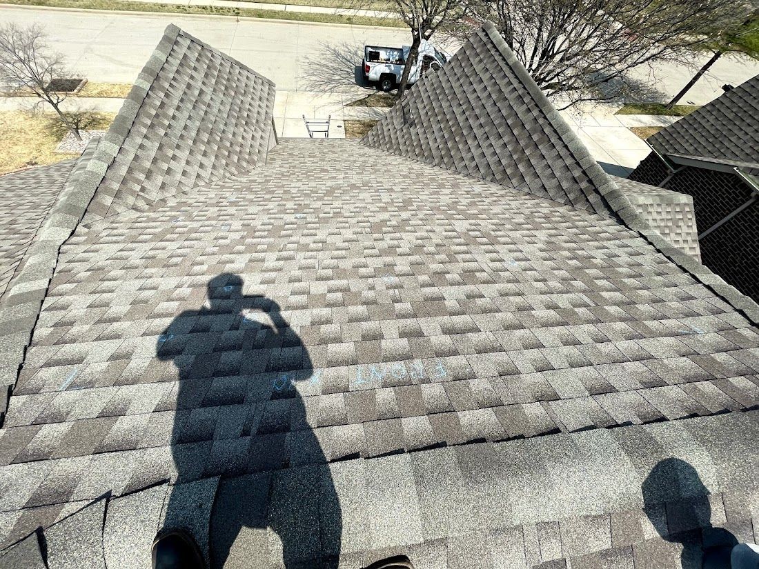 A shadow of a person is cast on the roof of a house.