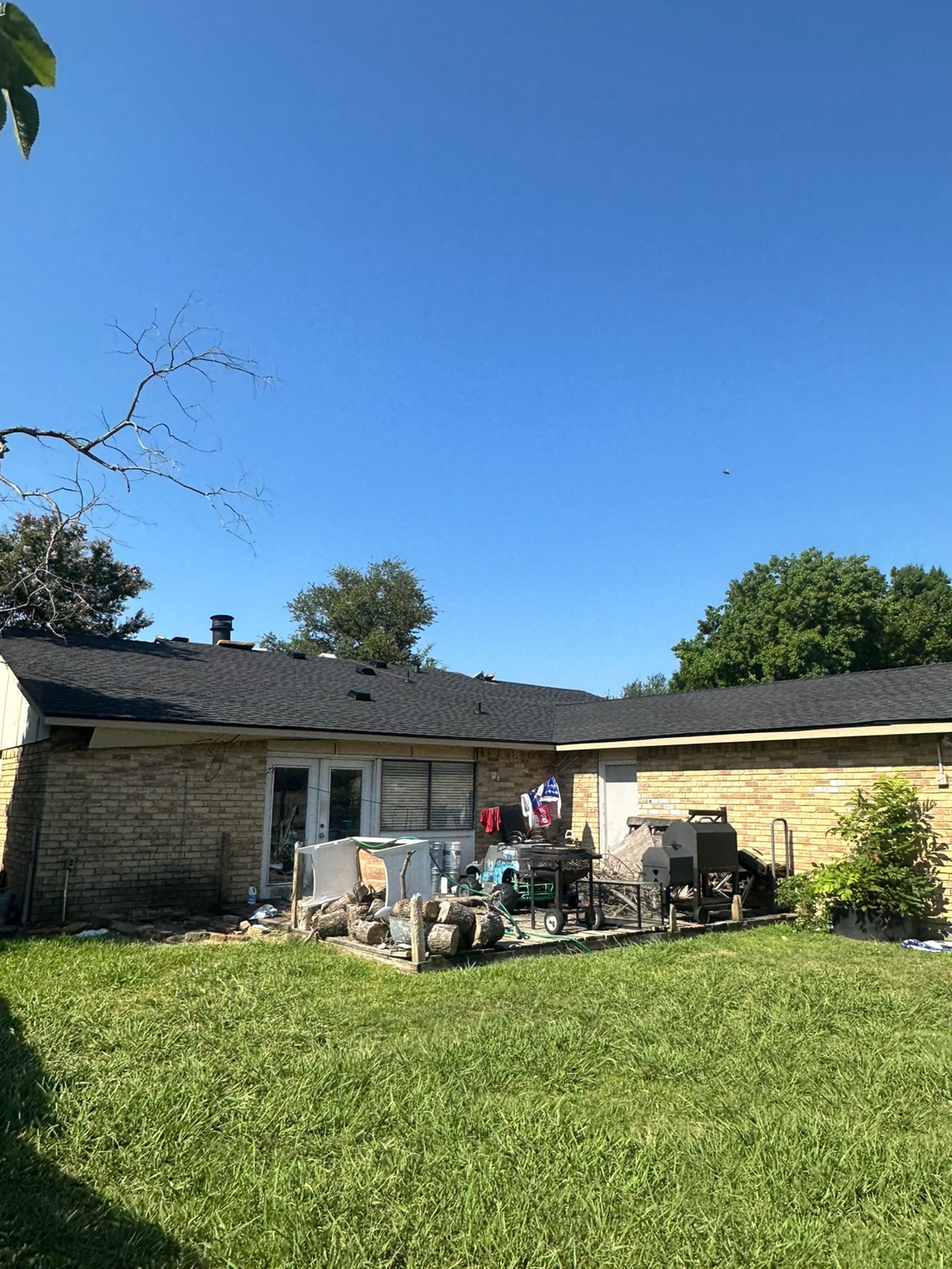 The backyard of a house with a large lawn and a roof.