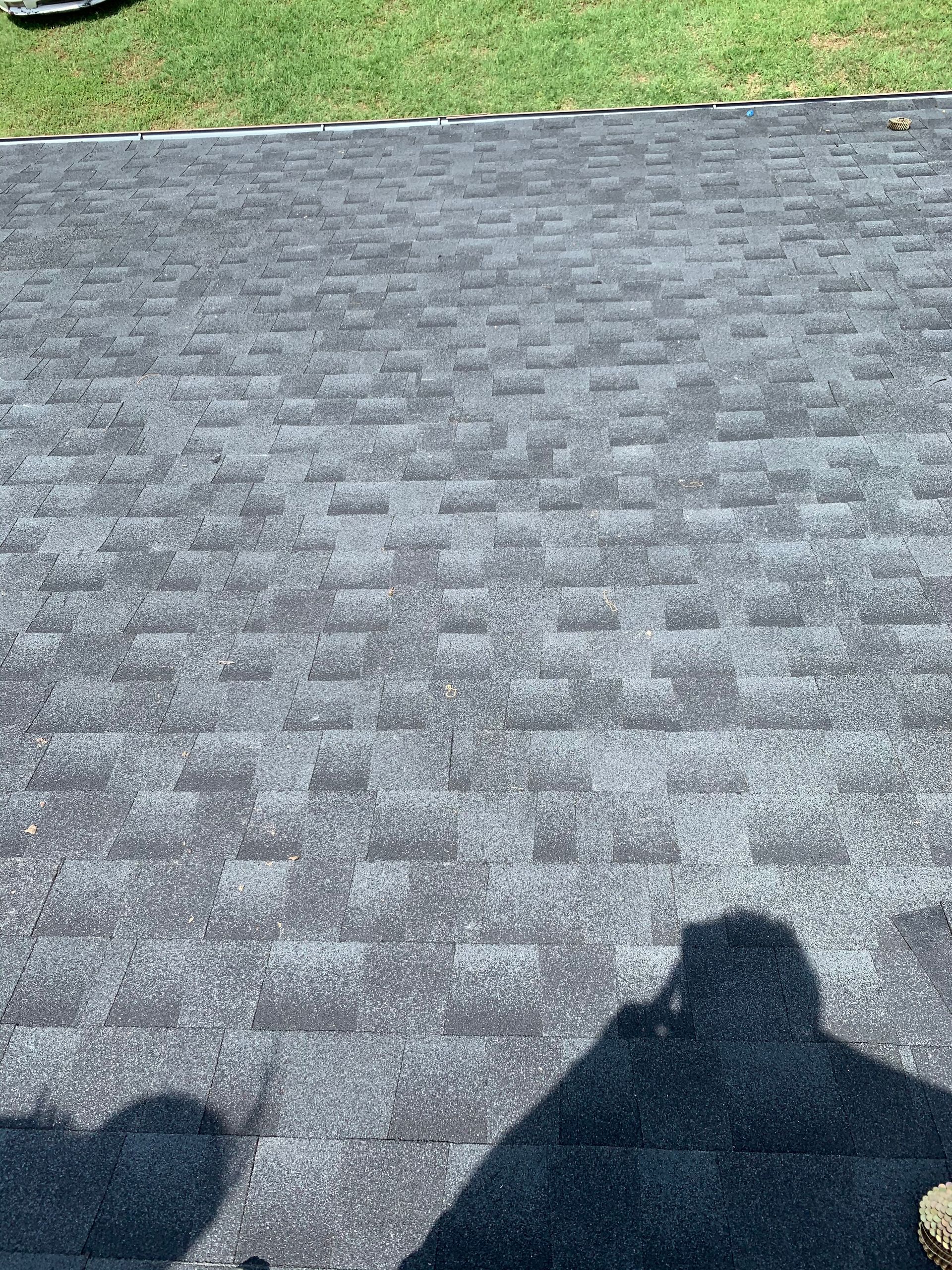 A shadow of a person is cast on a brick driveway.