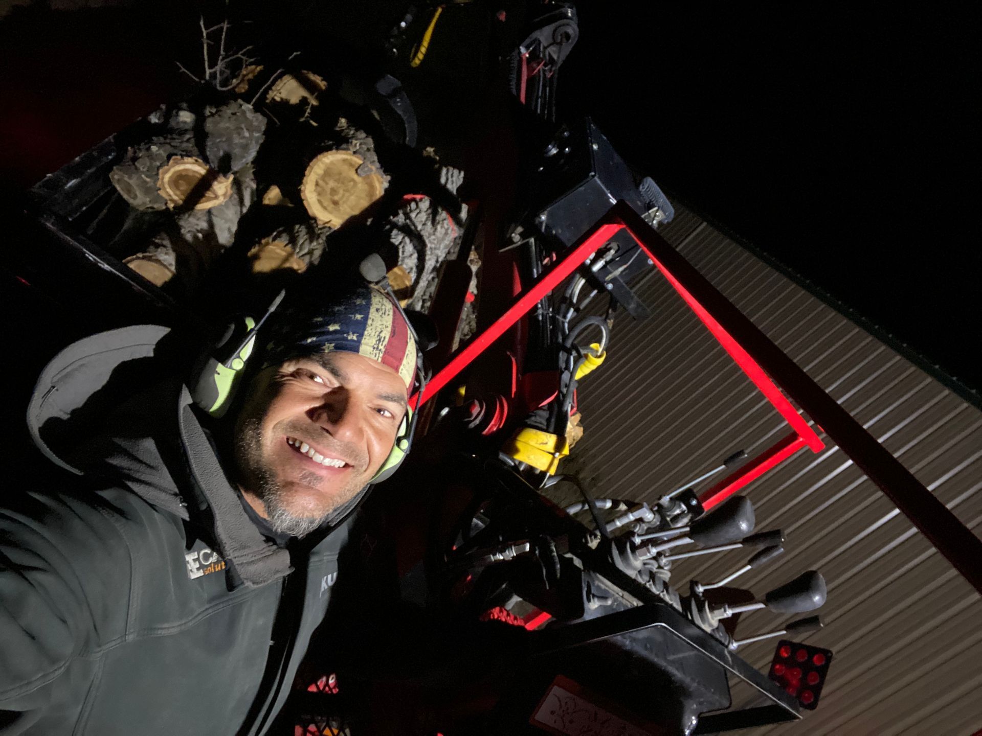 Smiling person in a headlamp on a dark rooftop, with solar panels and equipment around them