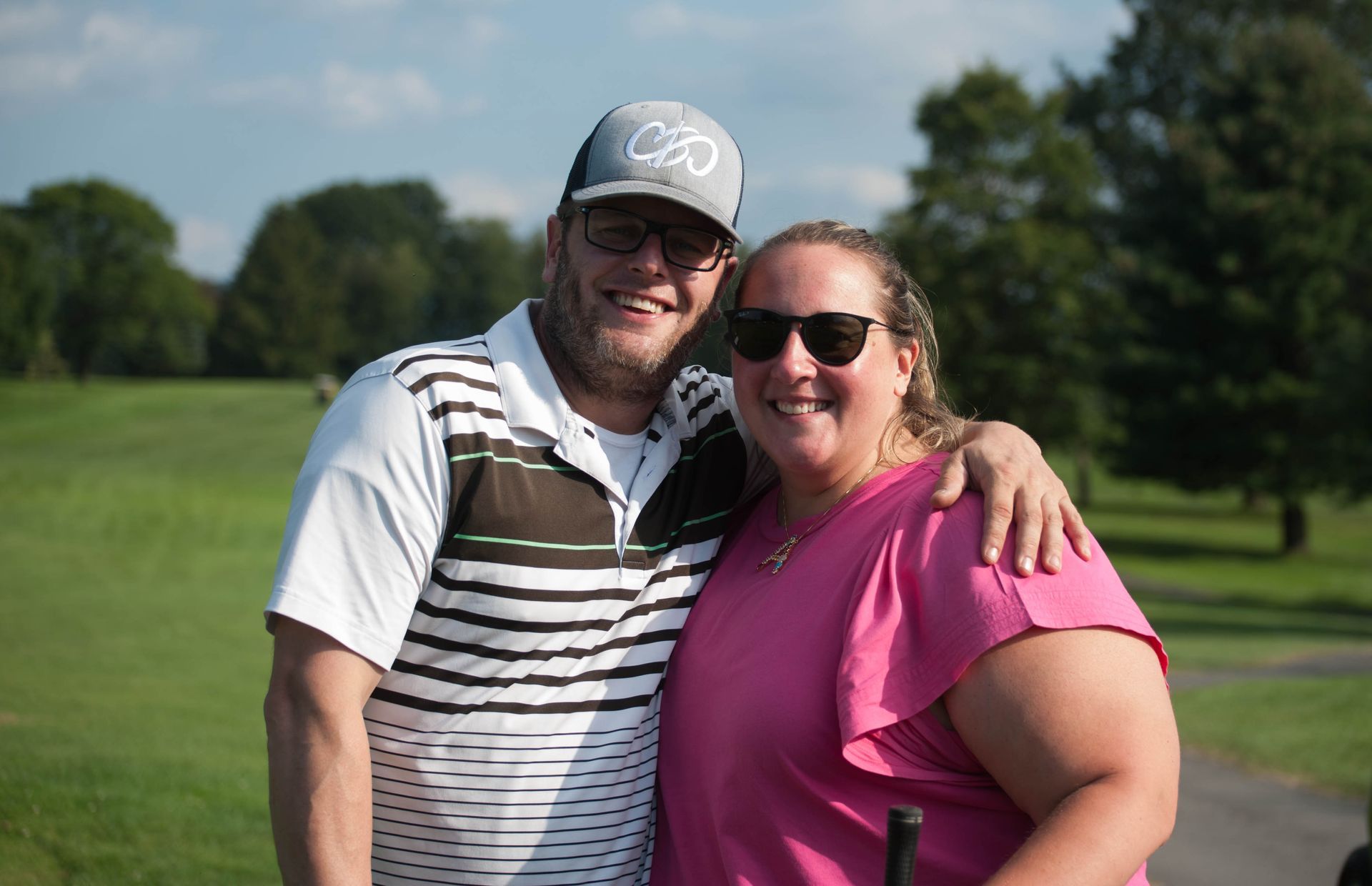 A man and a woman are posing for a picture on a golf course.