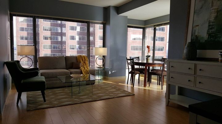 A living room with a couch , chair , table and large windows
