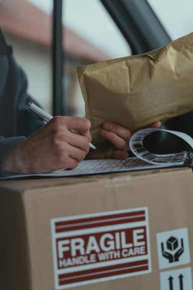 A person is writing on a piece of paper next to a box that says fragile handle with care