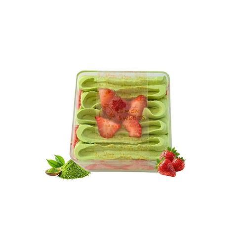 Green layered dessert topped with strawberries, with raspberries and mint leaves beside it