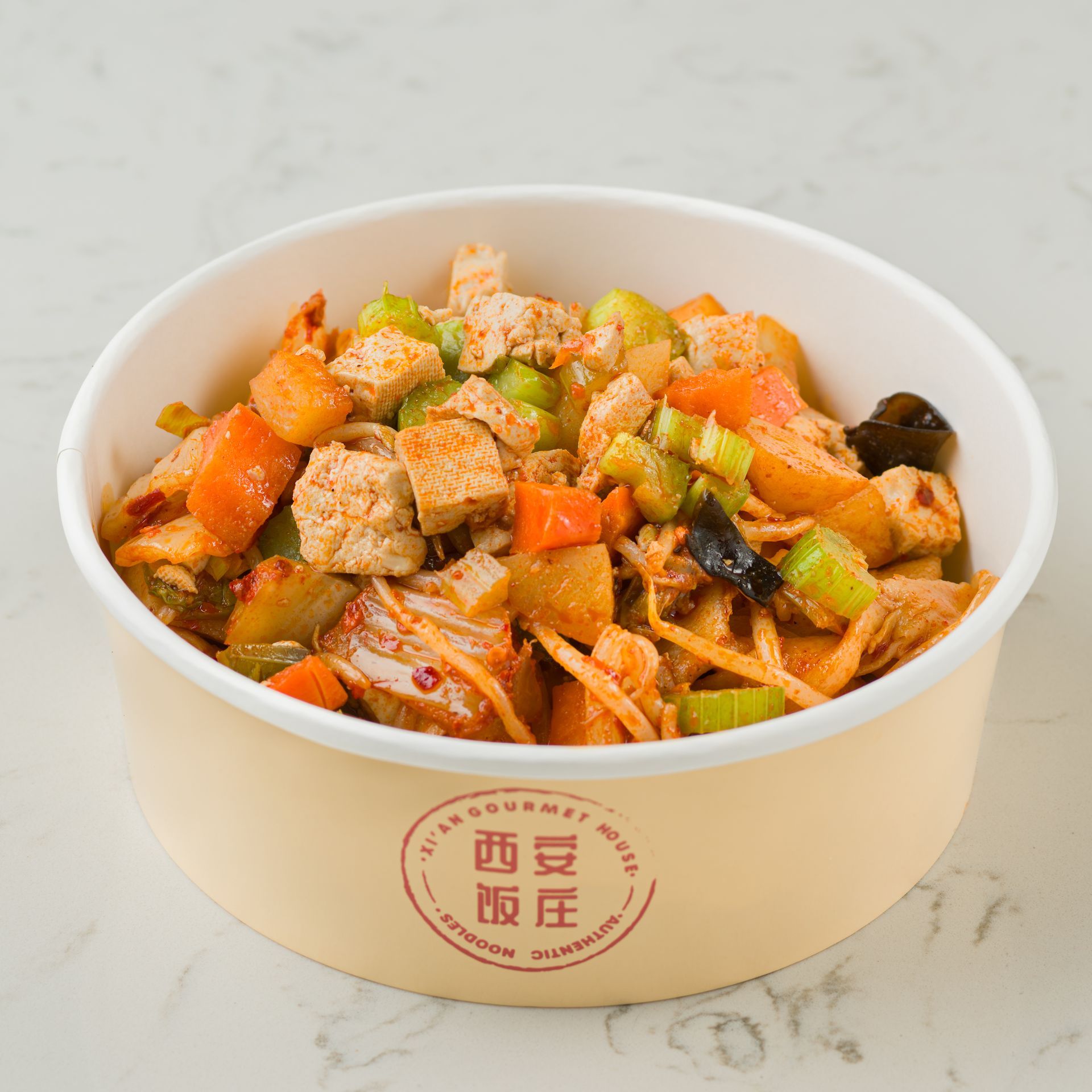 White bowl of diced tofu and vegetables in orange sauce, topped with herbs, on a light table