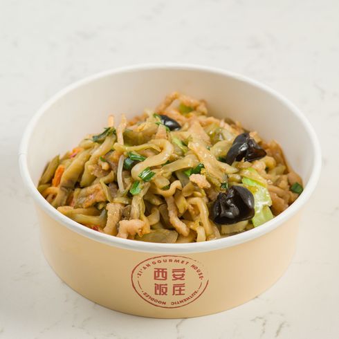 Paper bowl of stir-fried noodles with vegetables and mushrooms on a light background