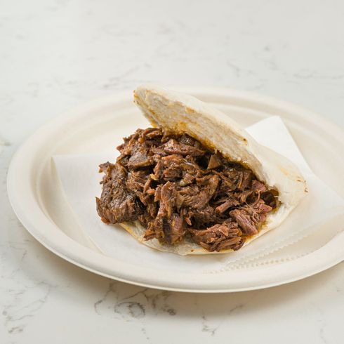 Pulled meat filling in a soft bun on a white plate