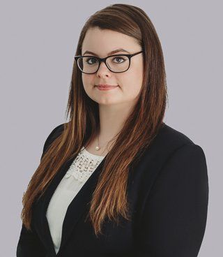 Christina Jones. Woman with dark hair, wearing glasses, a white top, and black blazer.
