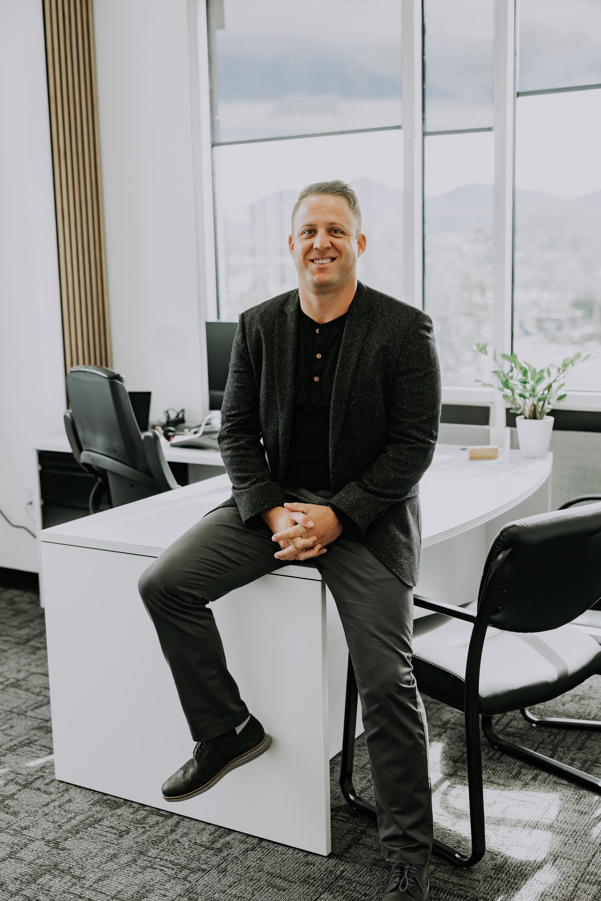 A man is sitting on a desk in an office.