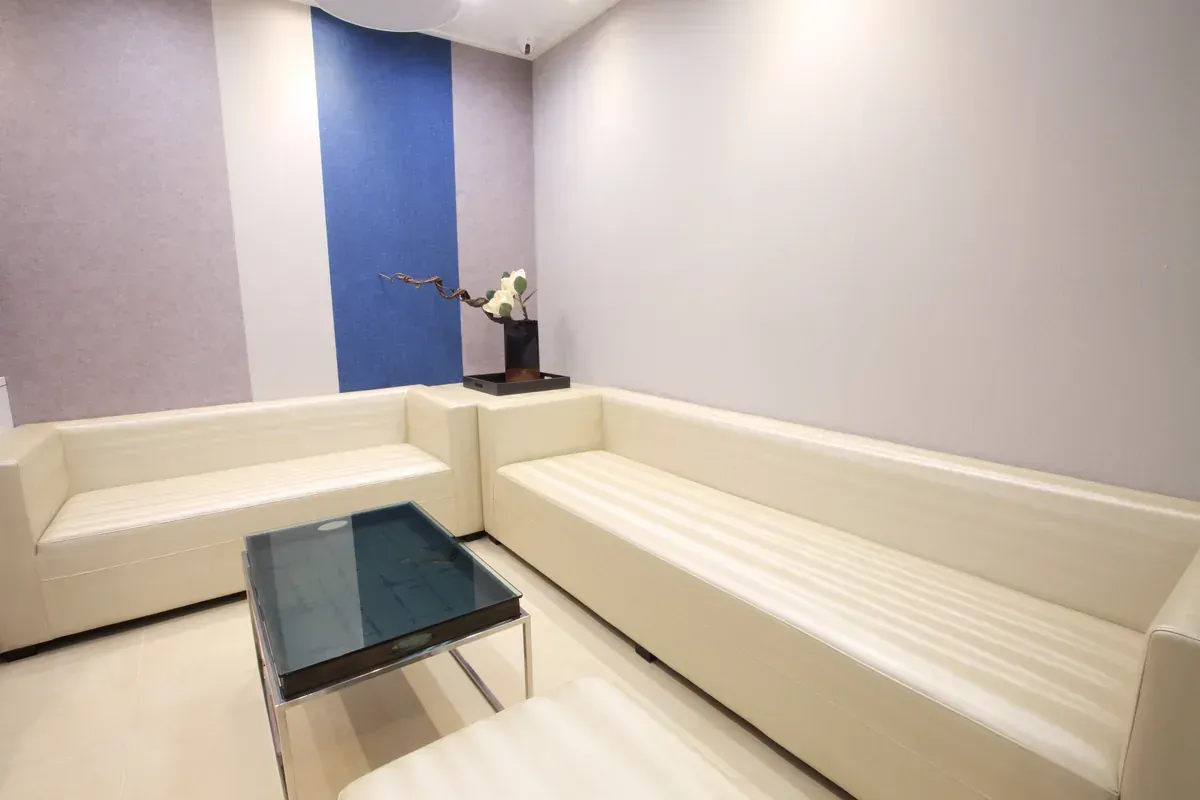 Modern minimalist room with a single bed, desk, chair, and warm backlit wall panel