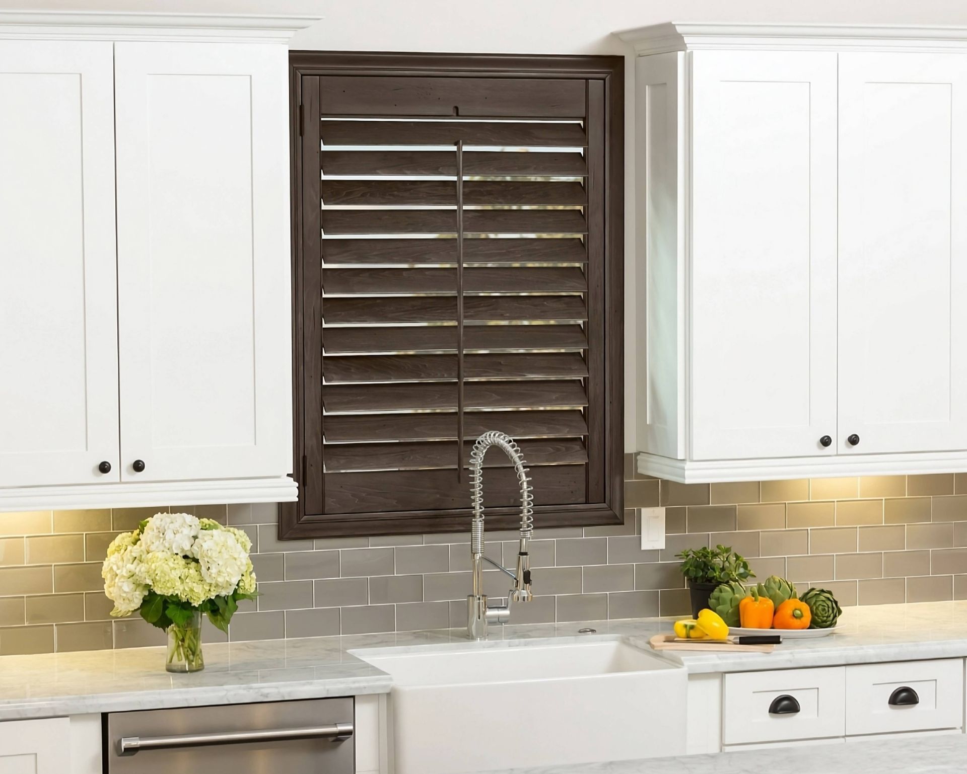 Dark wood Hunter Douglas Heritance® Wood Shutters on a window above a kitchen sink at Harmony Blinds