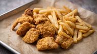 Fried chicken tenders and French fries on a parchment-lined tray