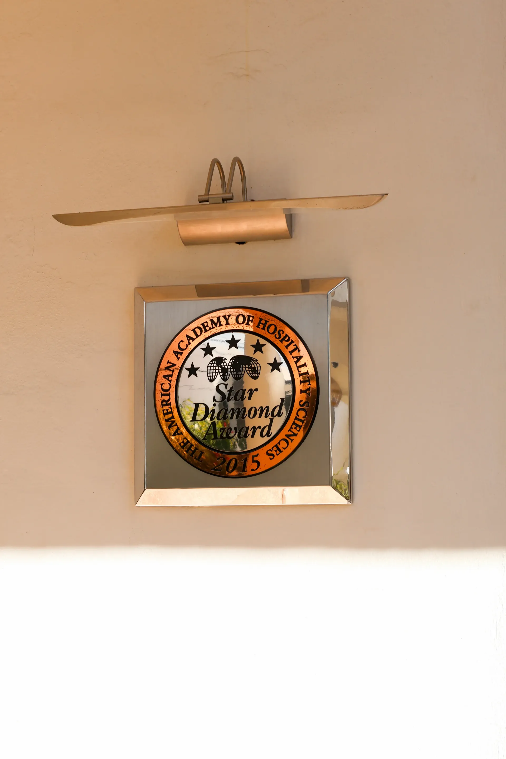 Placa mural con una insignia circular y una pequeña hélice encima, sobre una pared de color beige.