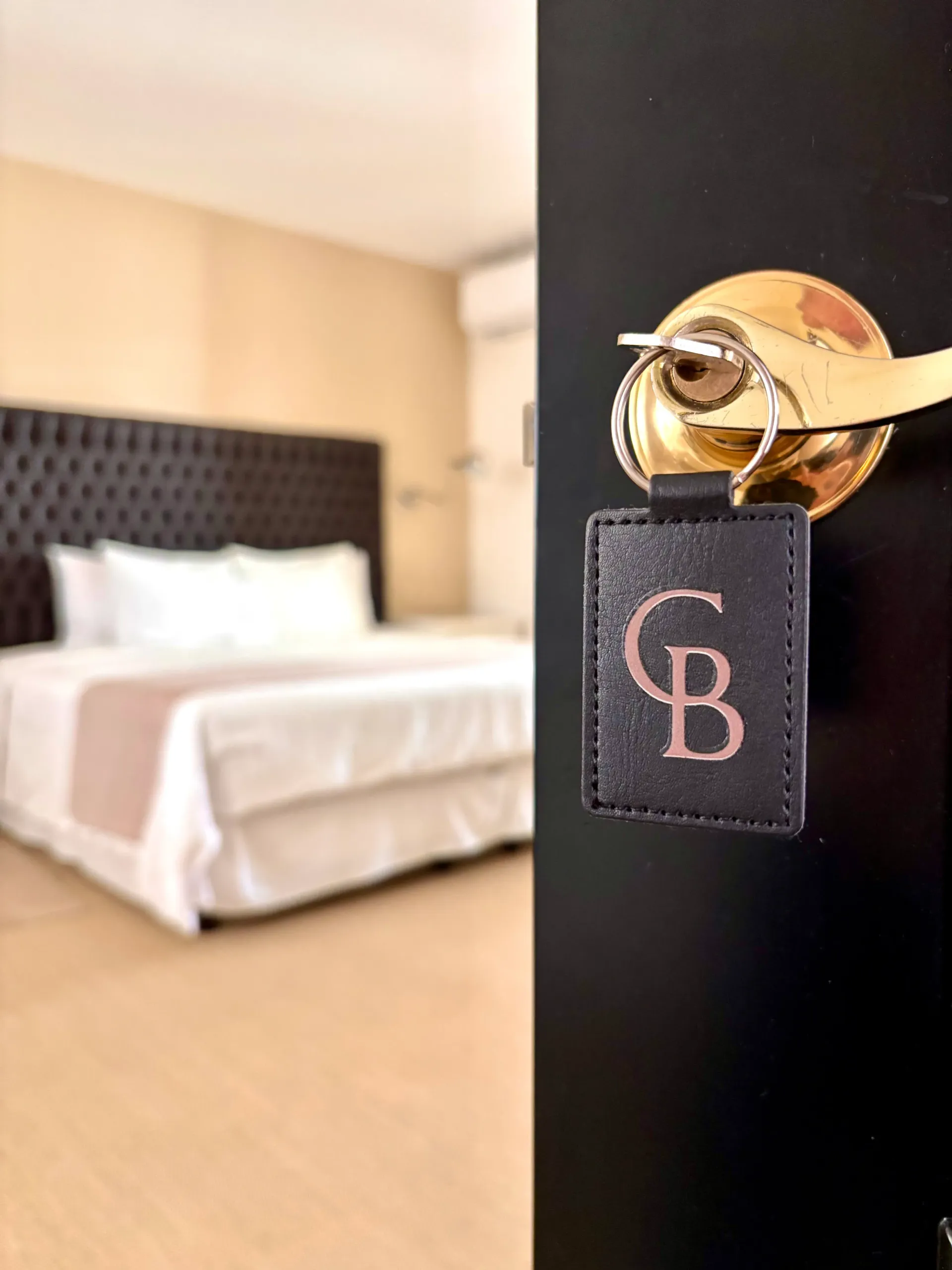 Puerta de habitación de hotel con manija dorada y llavero negro 