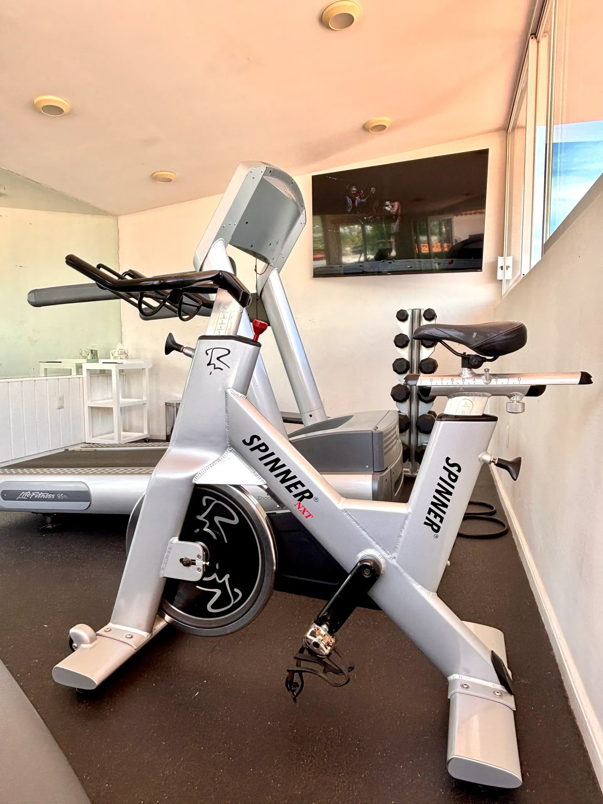 Bicicleta estática en un gimnasio luminoso con pared de espejos y ventanas en el hotel Casa Bonita en Oaxaca