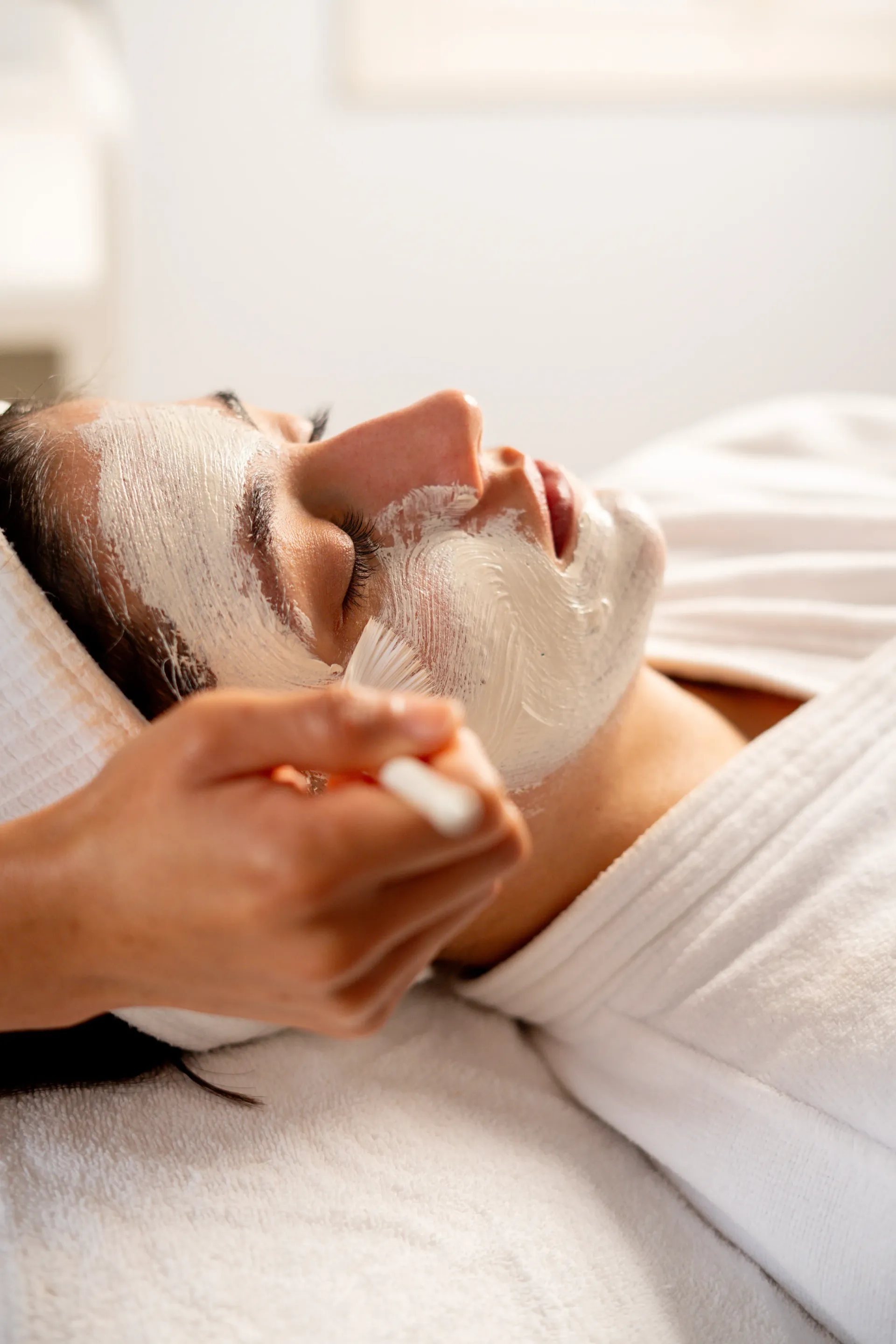 Persona recibiendo un tratamiento de mascarilla facial mientras está tumbada en una camilla de spa.