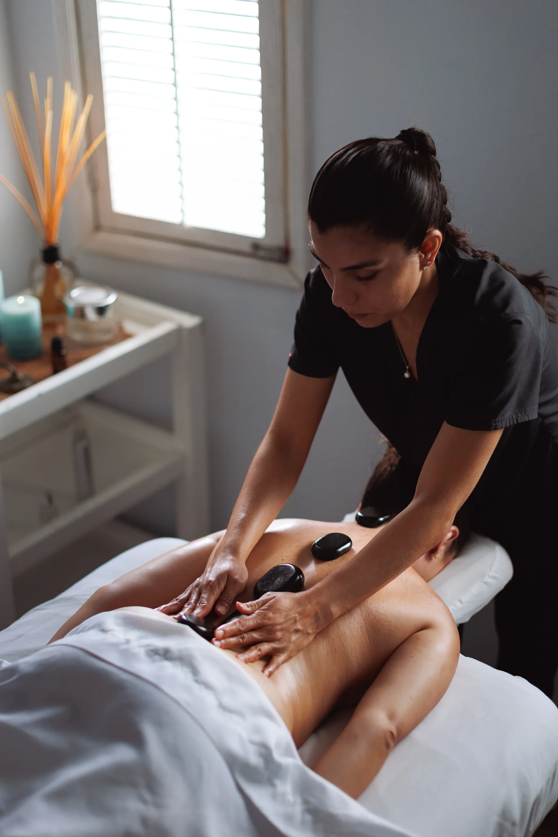 Masajista dando un masaje de espalda en una luminosa sala de spa.