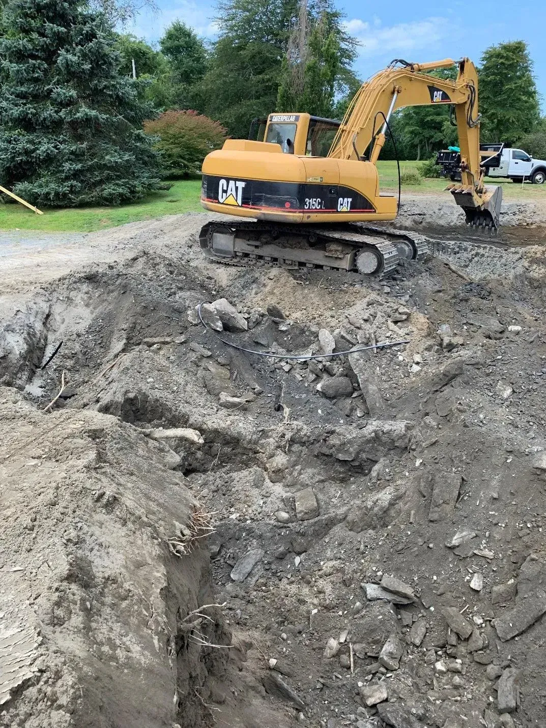 Yellow CAT excavator digging in a dirt pit outdoors.