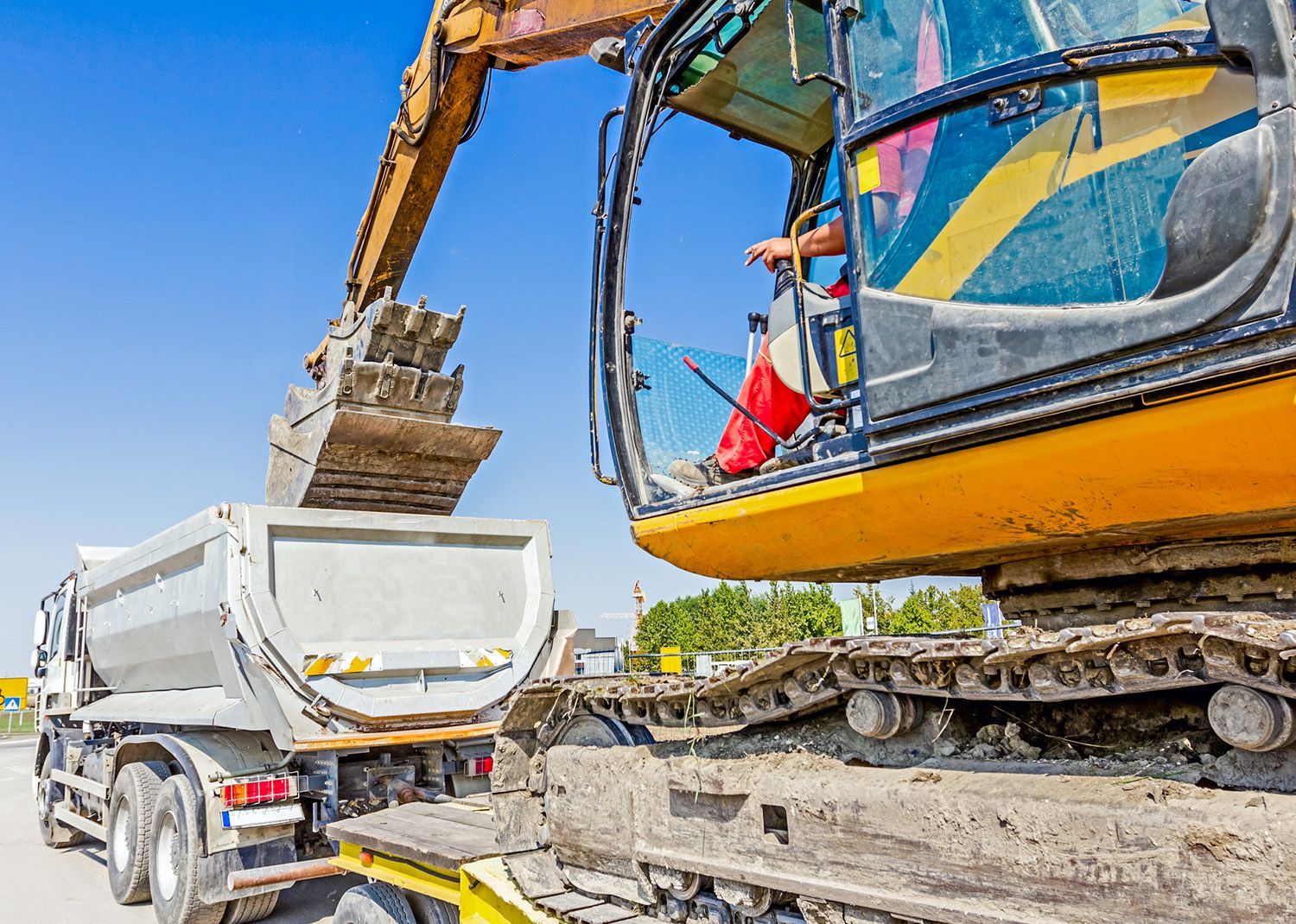 Excavator loading a dump truck with dirt at a construction site. Excavator loading a dump truck with dirt at a construction site.