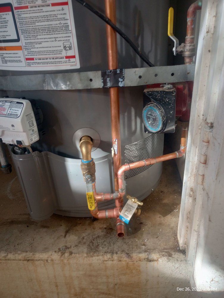 Copper pipes and fittings connected to a water heater and pump in a utility room.