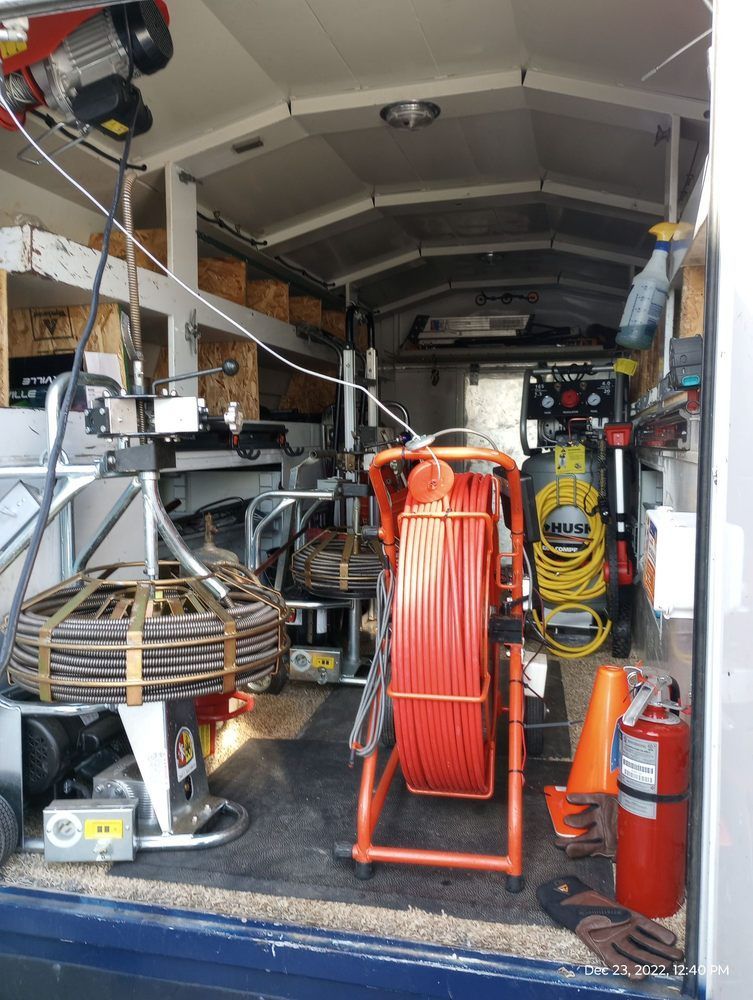 Inside of a utility truck, a cable reel and other equipment are stored.