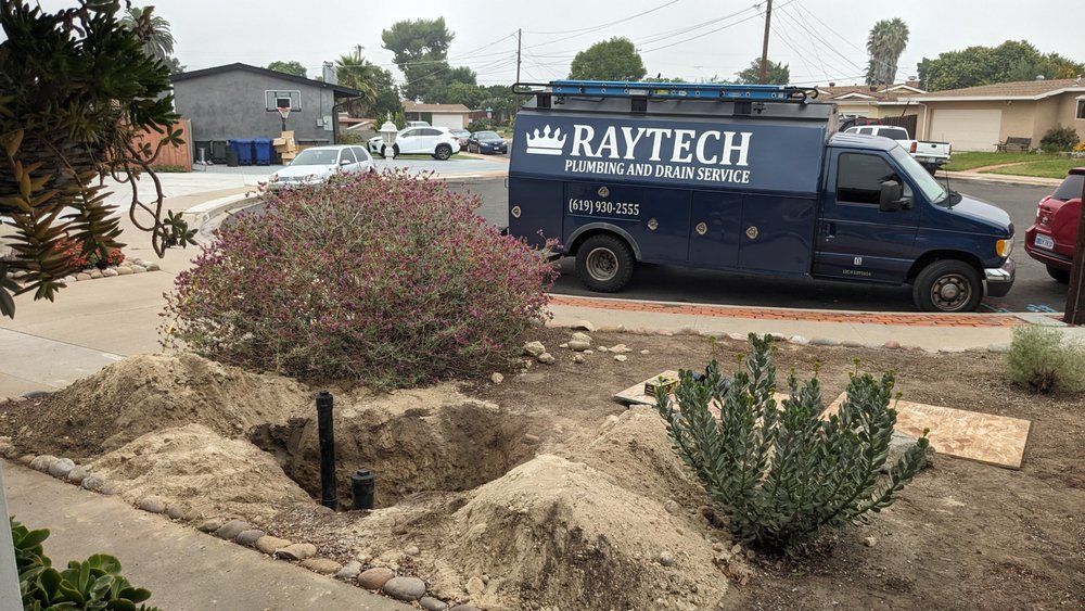 Exterior scene with RayTech service van, landscaping with dirt mounds and bushes.