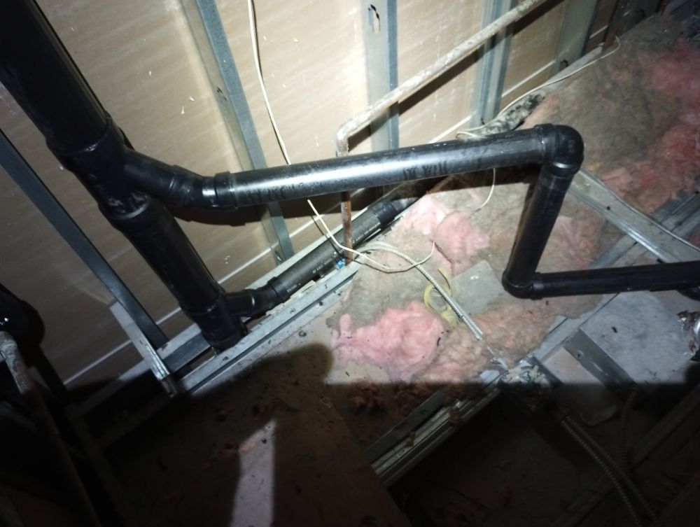 Black plumbing pipes installed in an attic space.