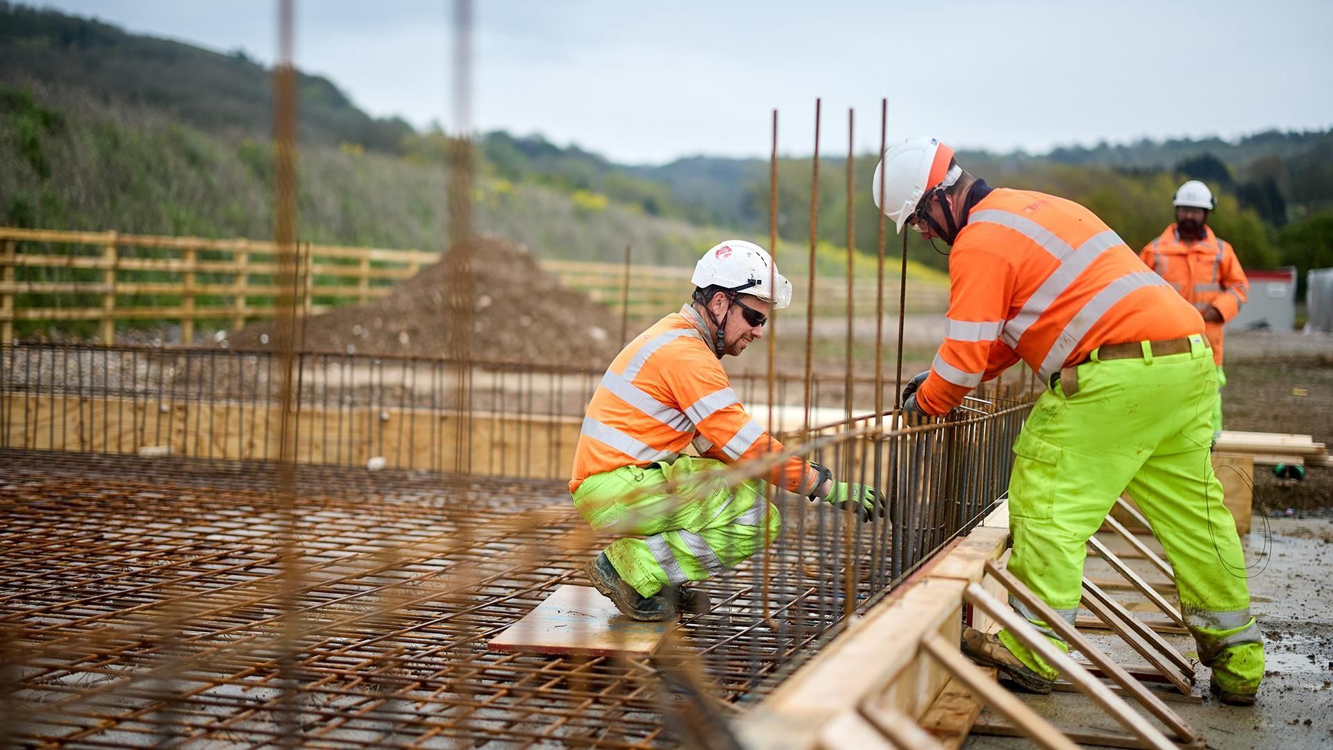 Construction workers pouring concrete on a foundation with rebar.