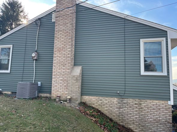 A two-story house with red horizontal siding on the top level and a light-colored brick exterior on the bottom level.
