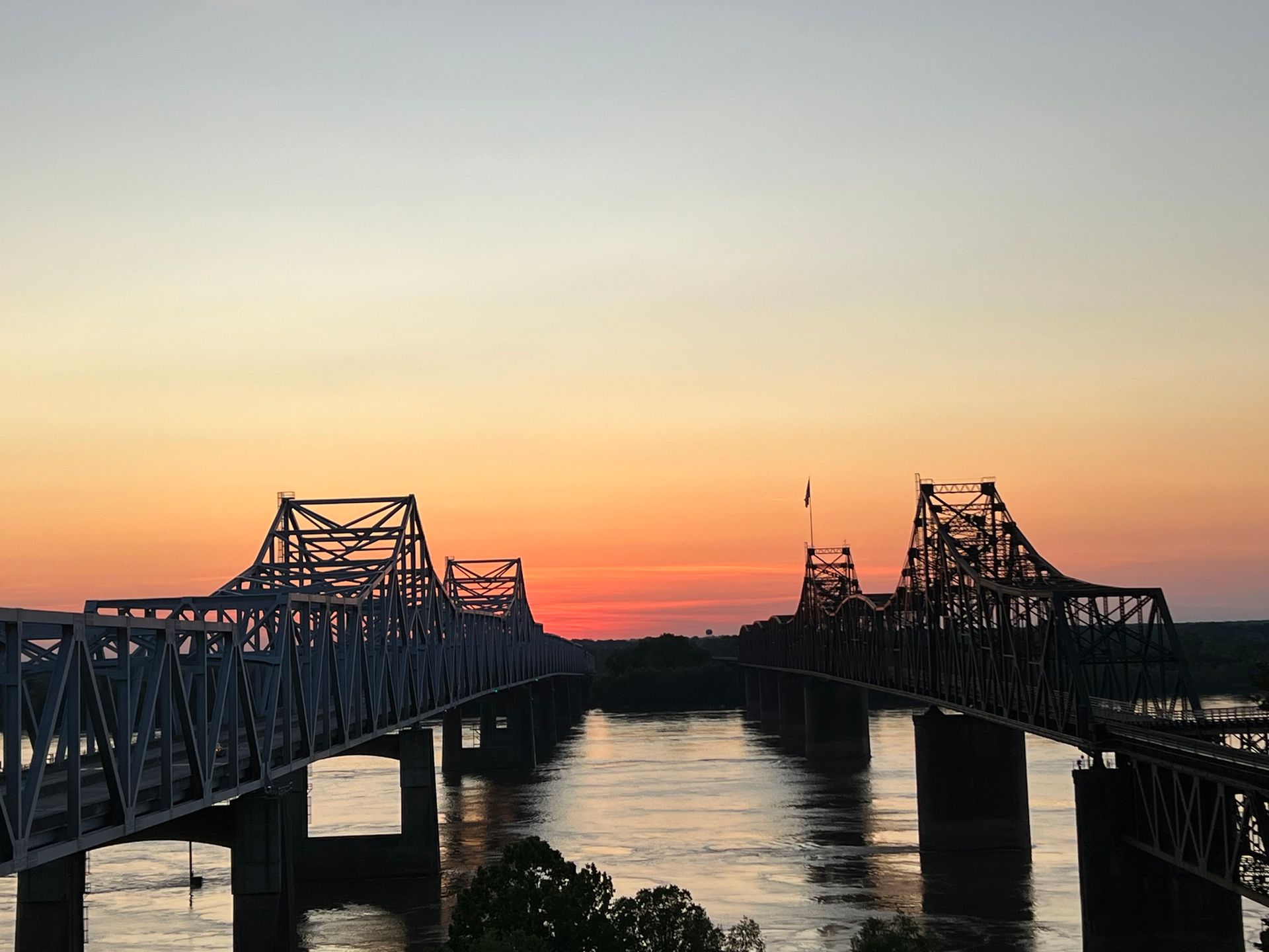 Two bridges over a river at sunset. Orange and yellow sky.