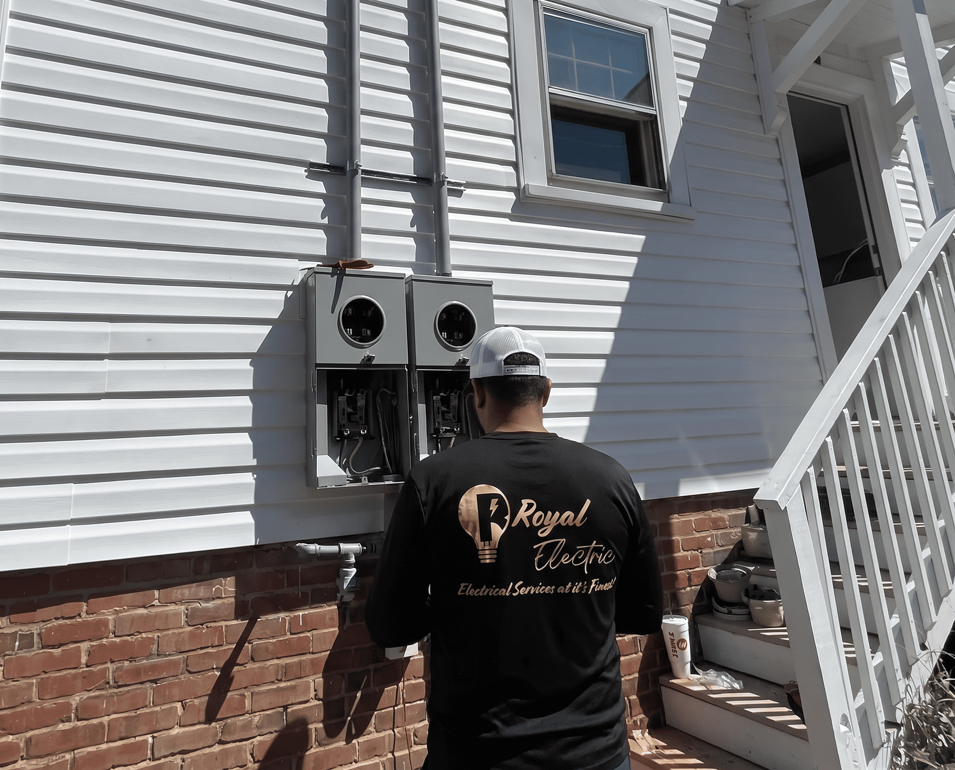 Worker inspecting outdoor electrical meters on a house exterior
