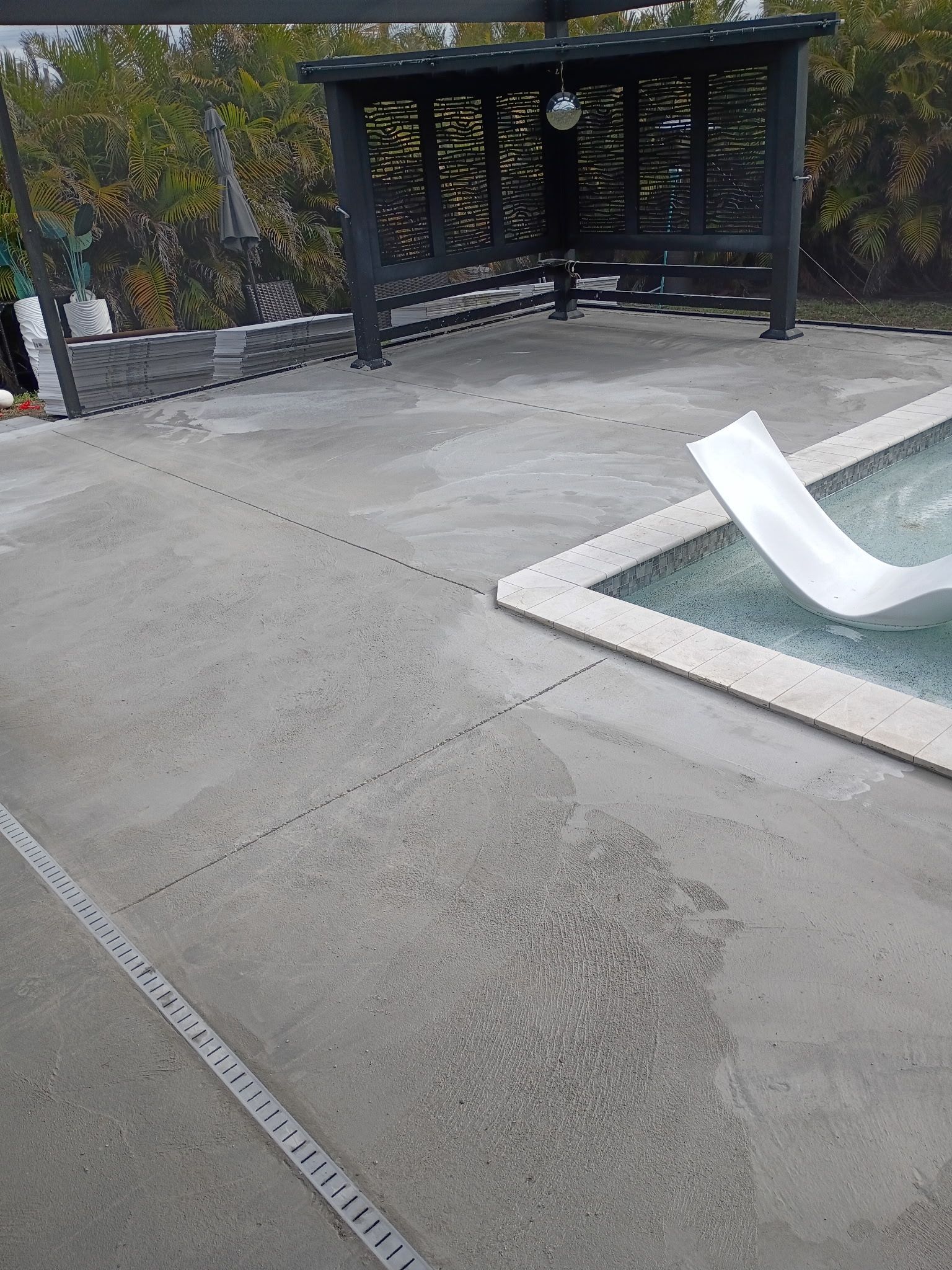 Outdoor concrete plaza with a dark pavilion, stone steps, and a white curved bench beside a fountain.