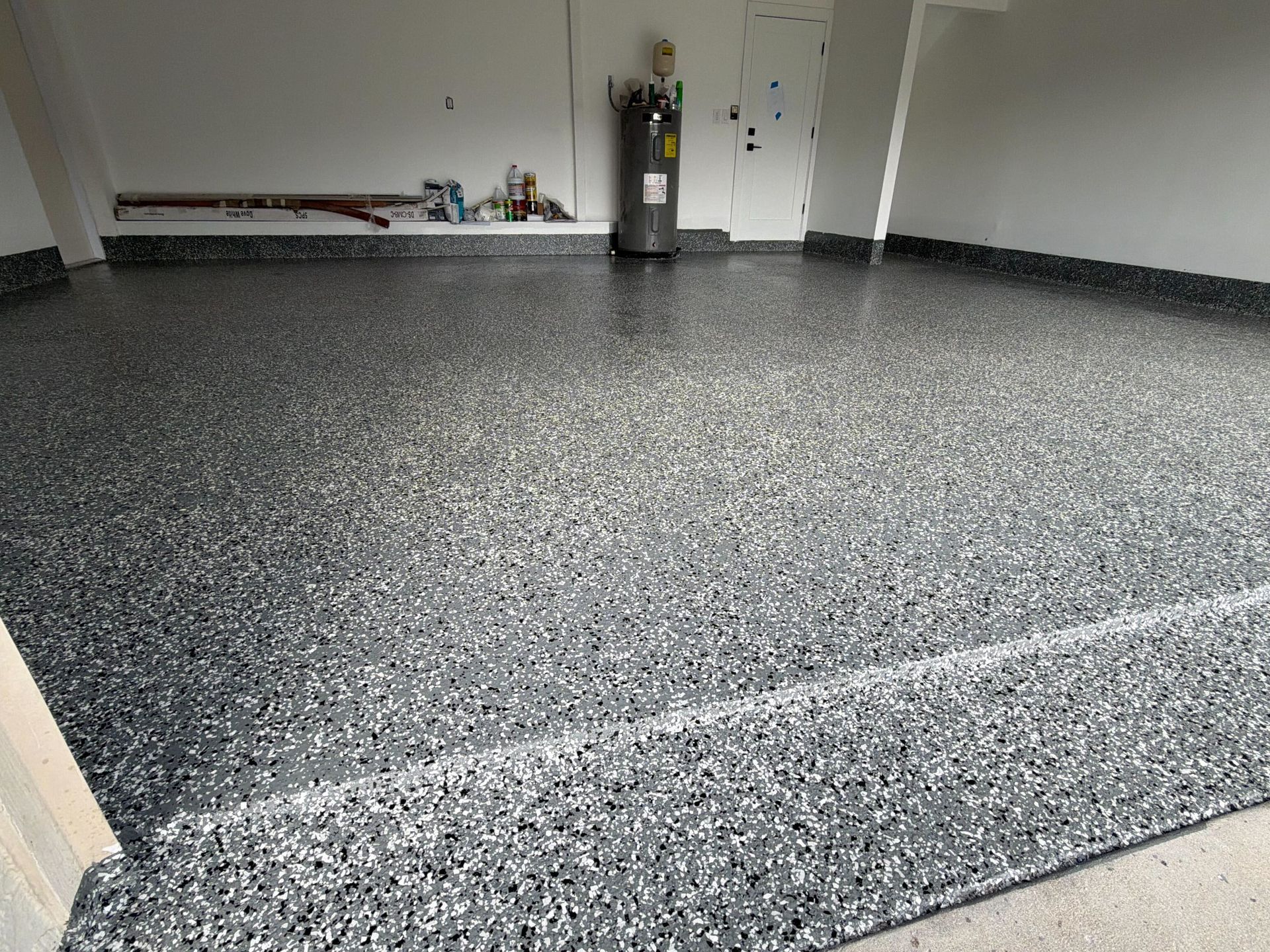 Empty room with speckled gray floor, white walls, and a fire extinguisher near the back wall.