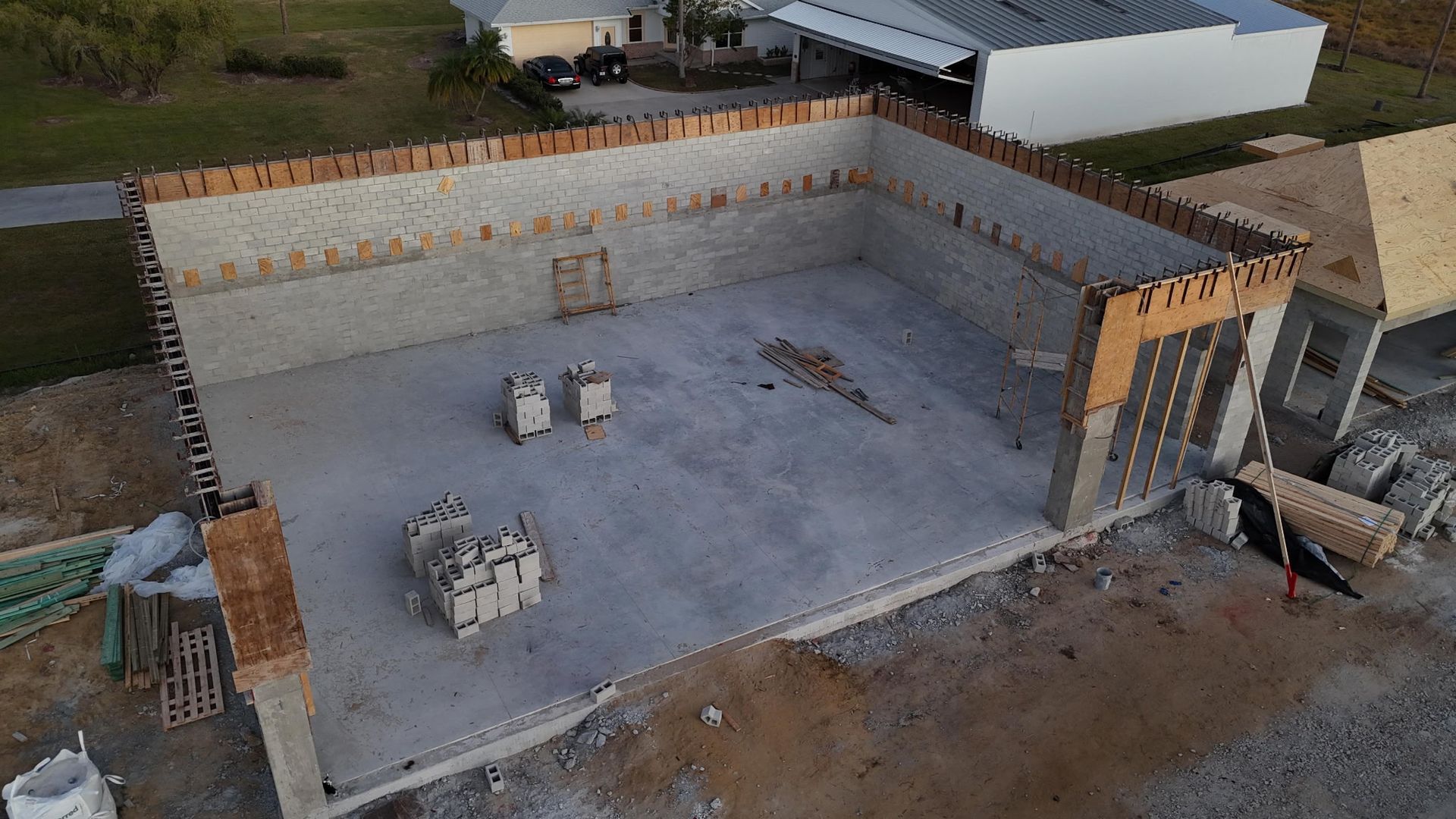 Aerial view of a concrete foundation under construction, with block walls and scattered materials.
