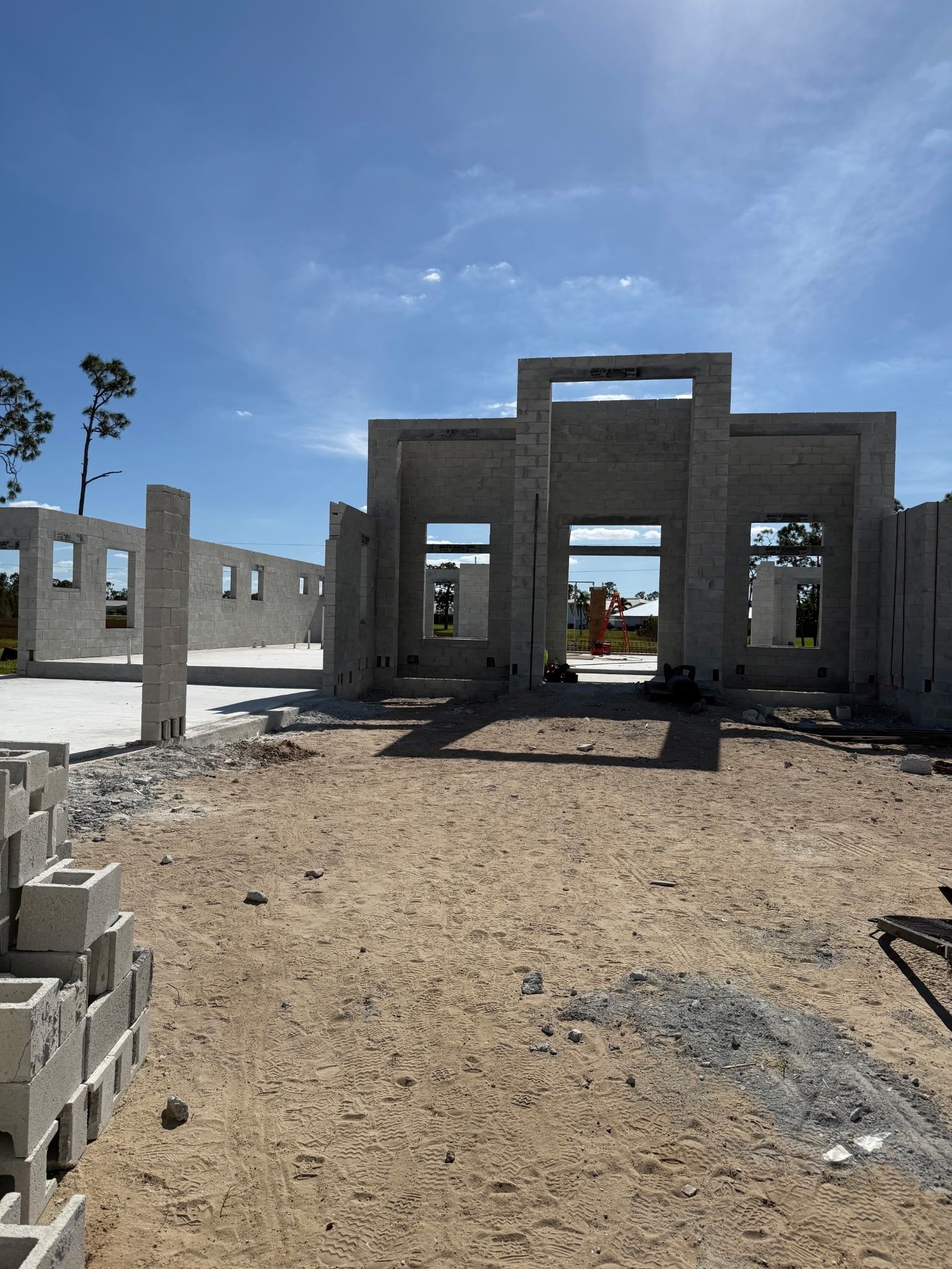 Partially constructed concrete building under a blue sky on a gravel site