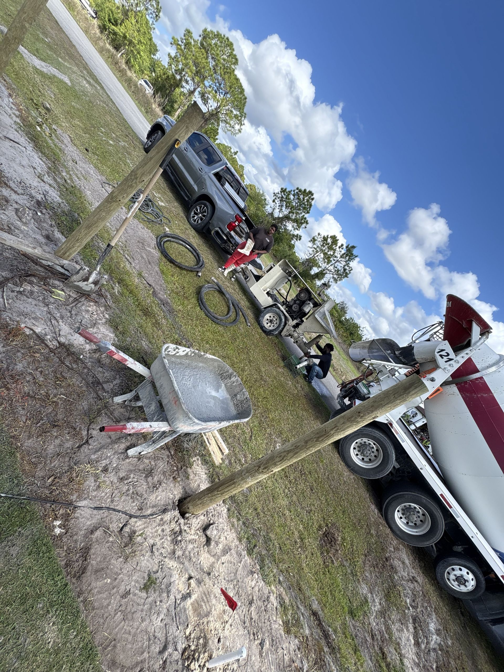 Wrecked truck and trailer in a grassy roadside area under a blue sky with scattered clouds