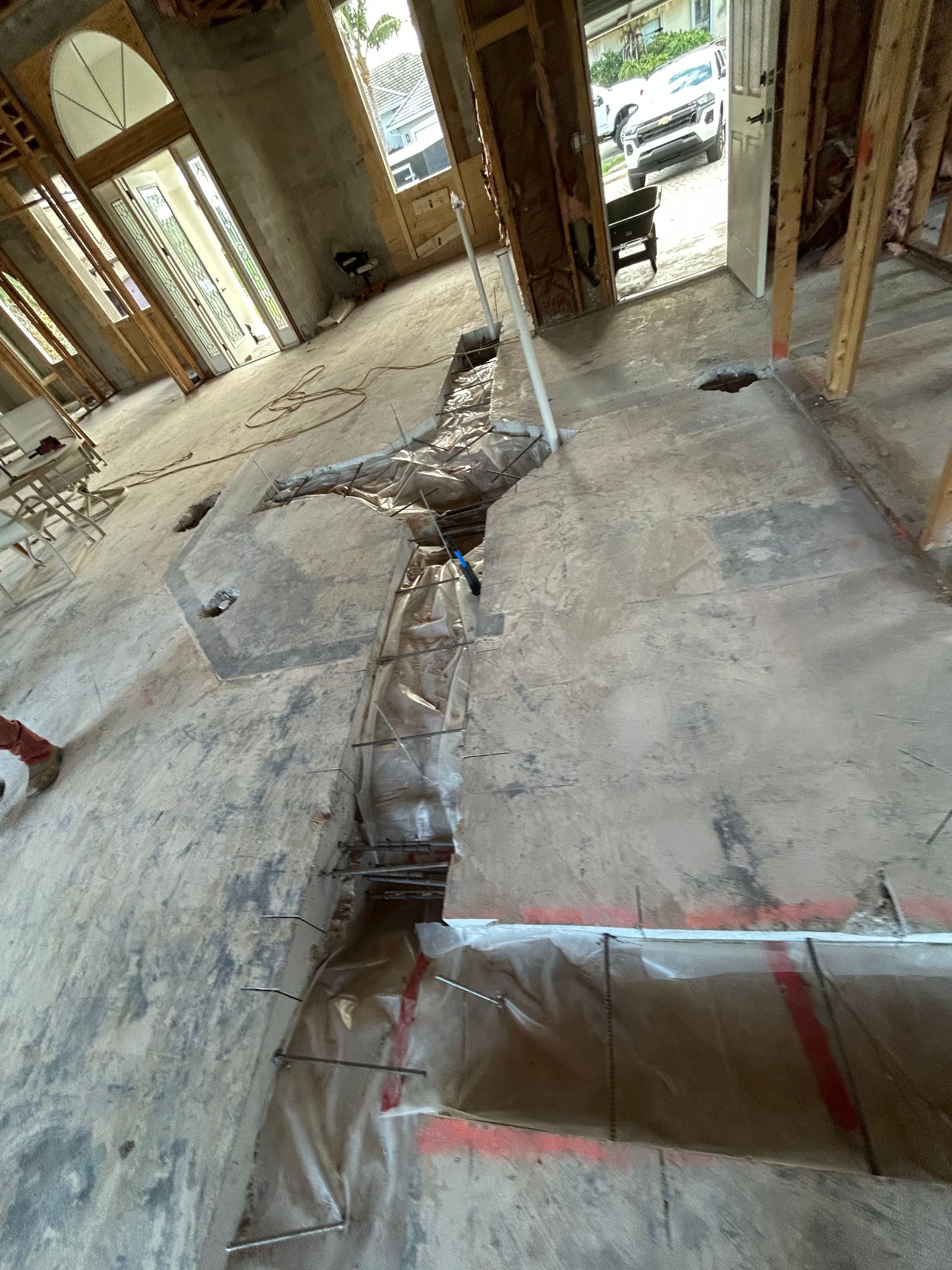 Construction site interior with a large crack in the concrete floor, possibly for a doorway.