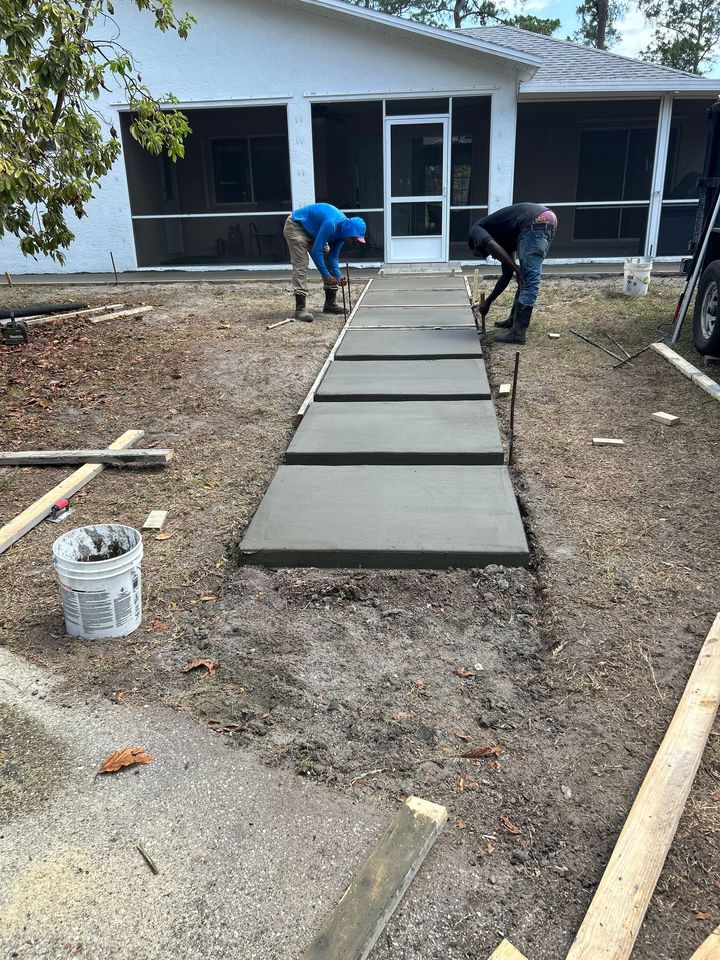 A group of construction workers are working on a concrete driveway.