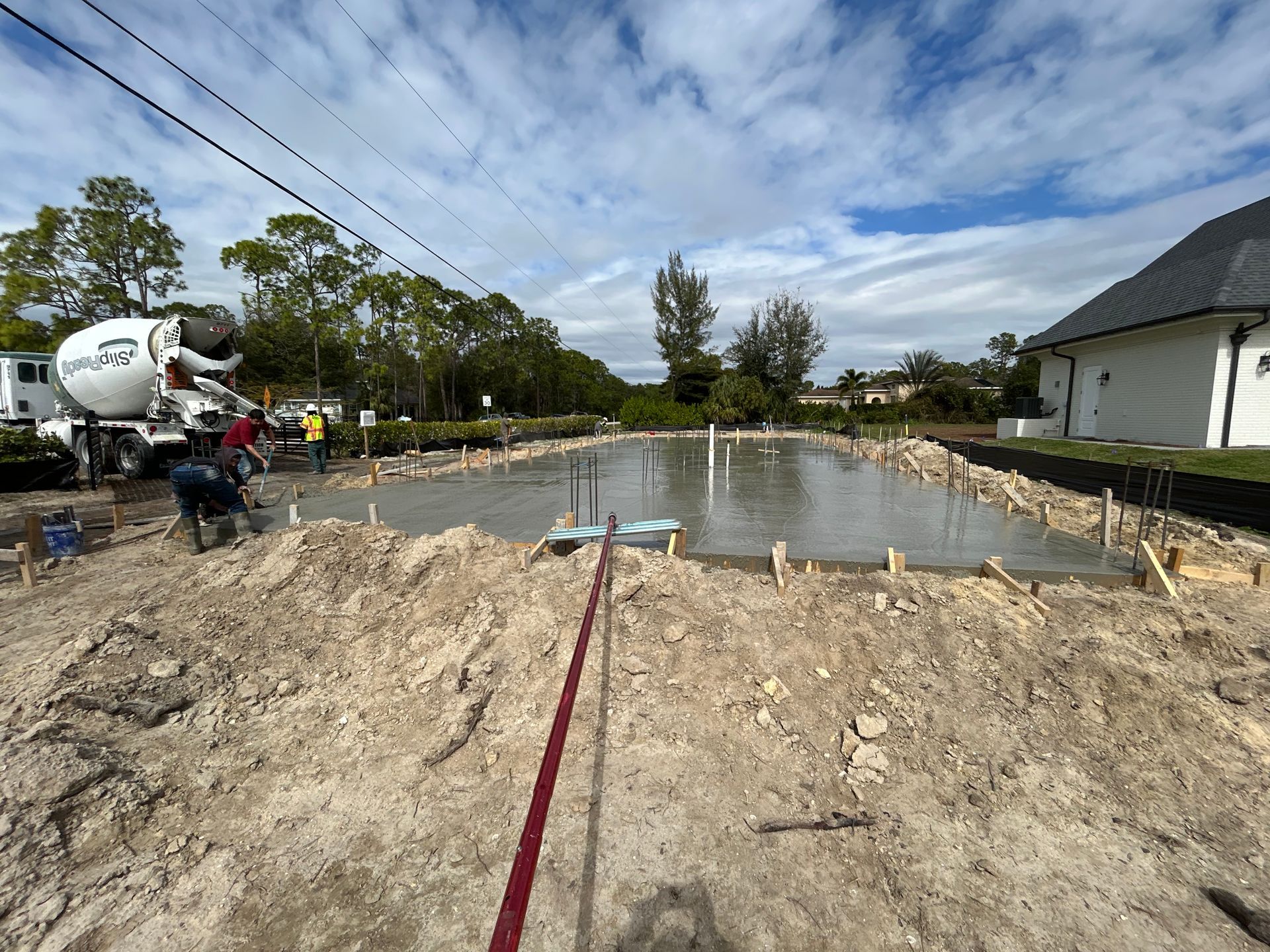 Construction site with concrete foundation slab, rebar forms, and a cement mixer truck nearby
