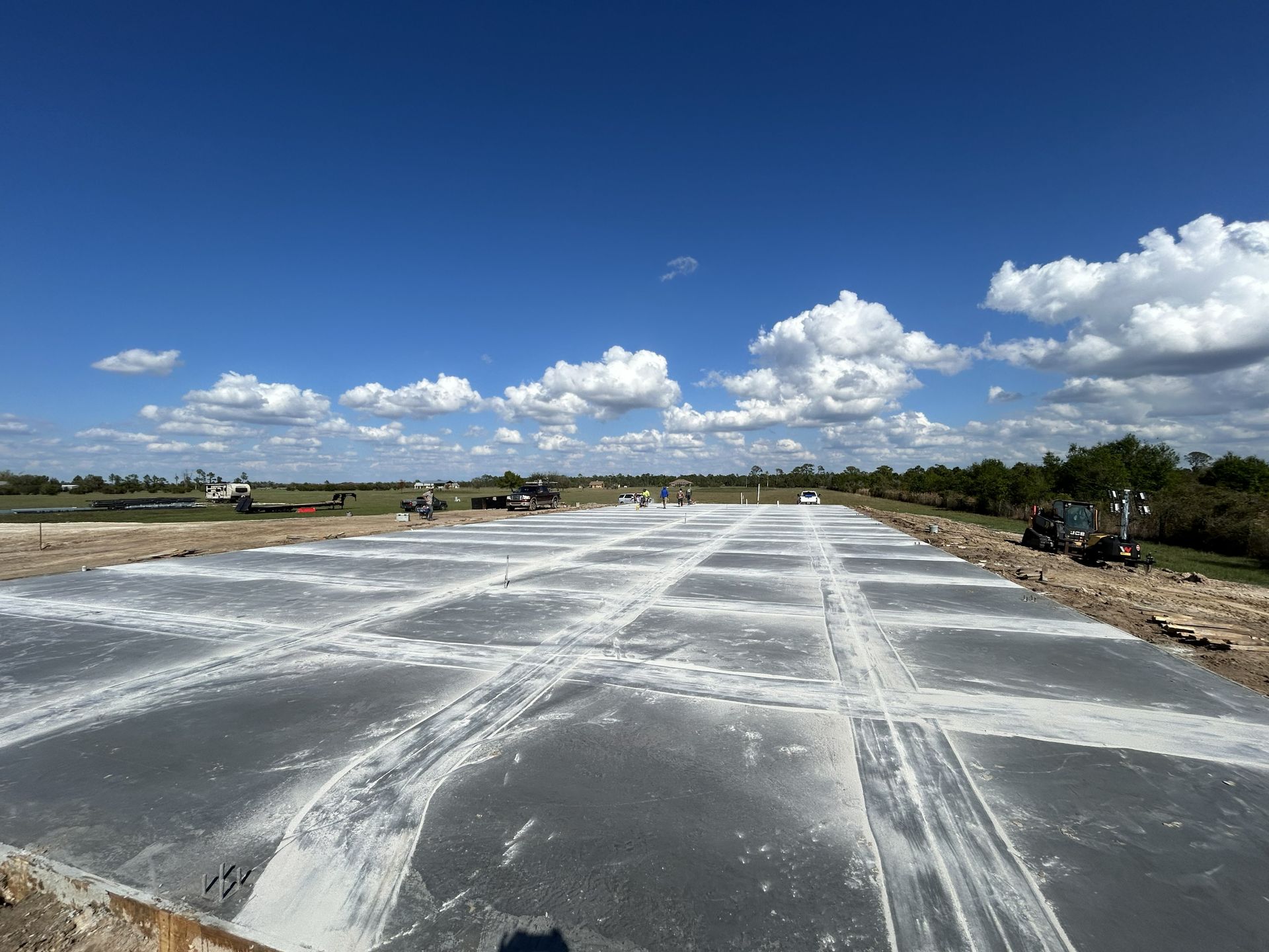 Empty concrete roadway under construction beneath a blue sky with scattered clouds