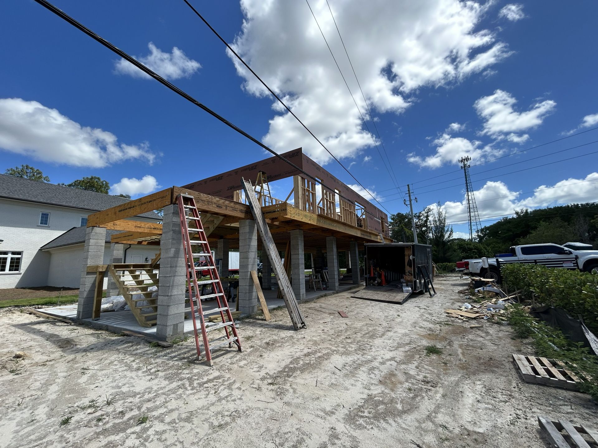 Construction site with a partially built house, ladders, scaffolding, and a blue sky overhead