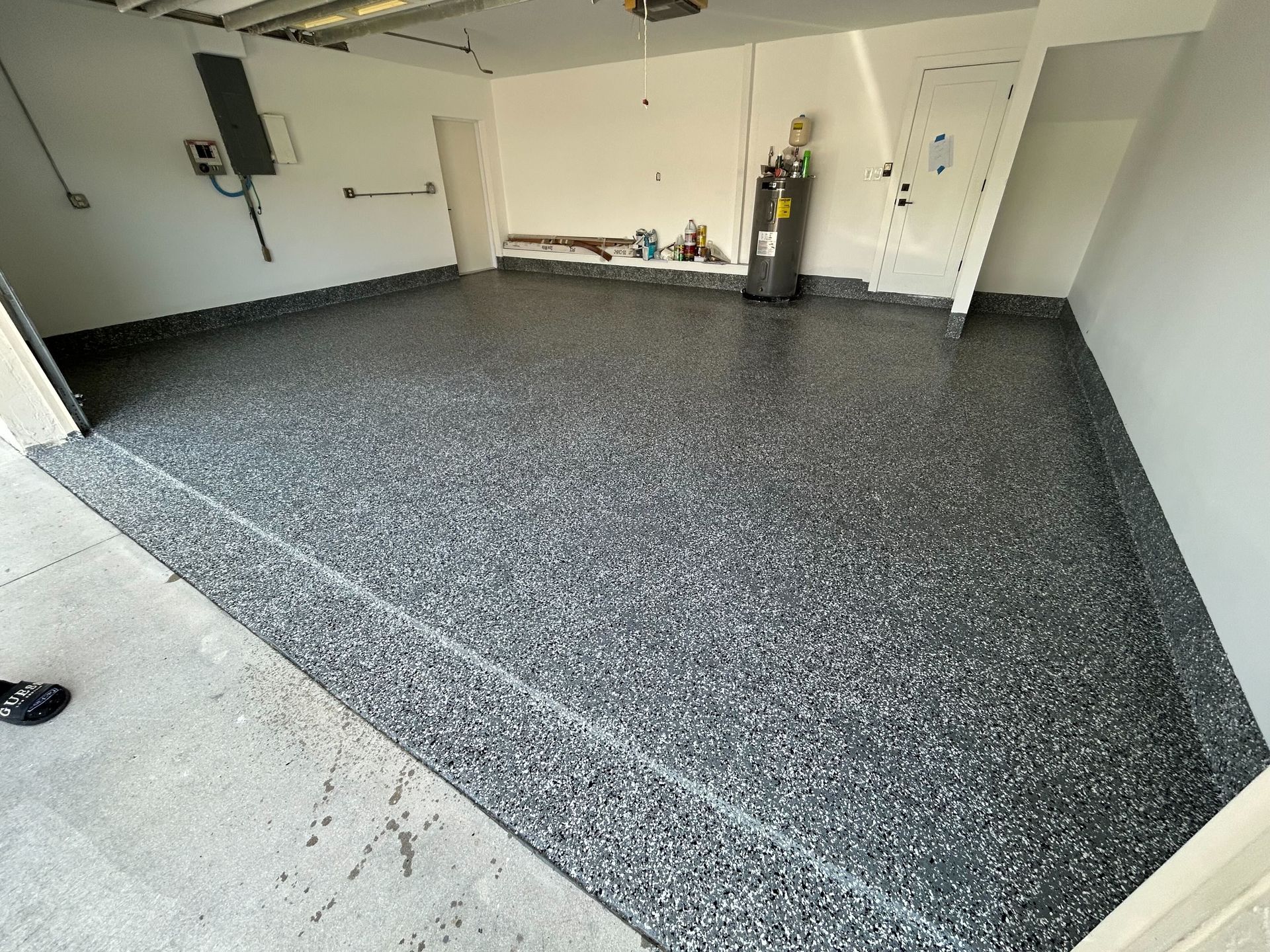 Empty garage with a speckled gray epoxy floor and white walls, viewed from the doorway