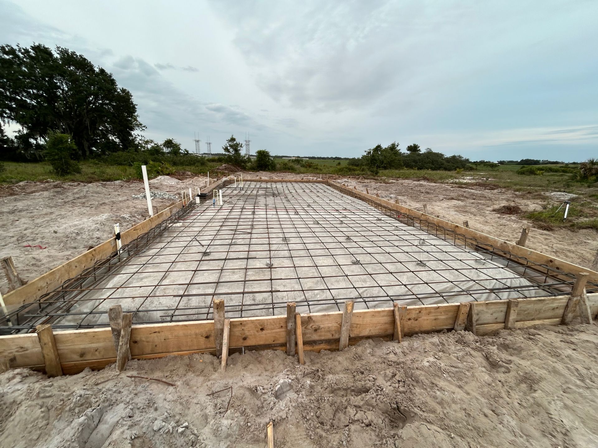 Concrete foundation slab with rebar grid and wooden formwork at a construction site