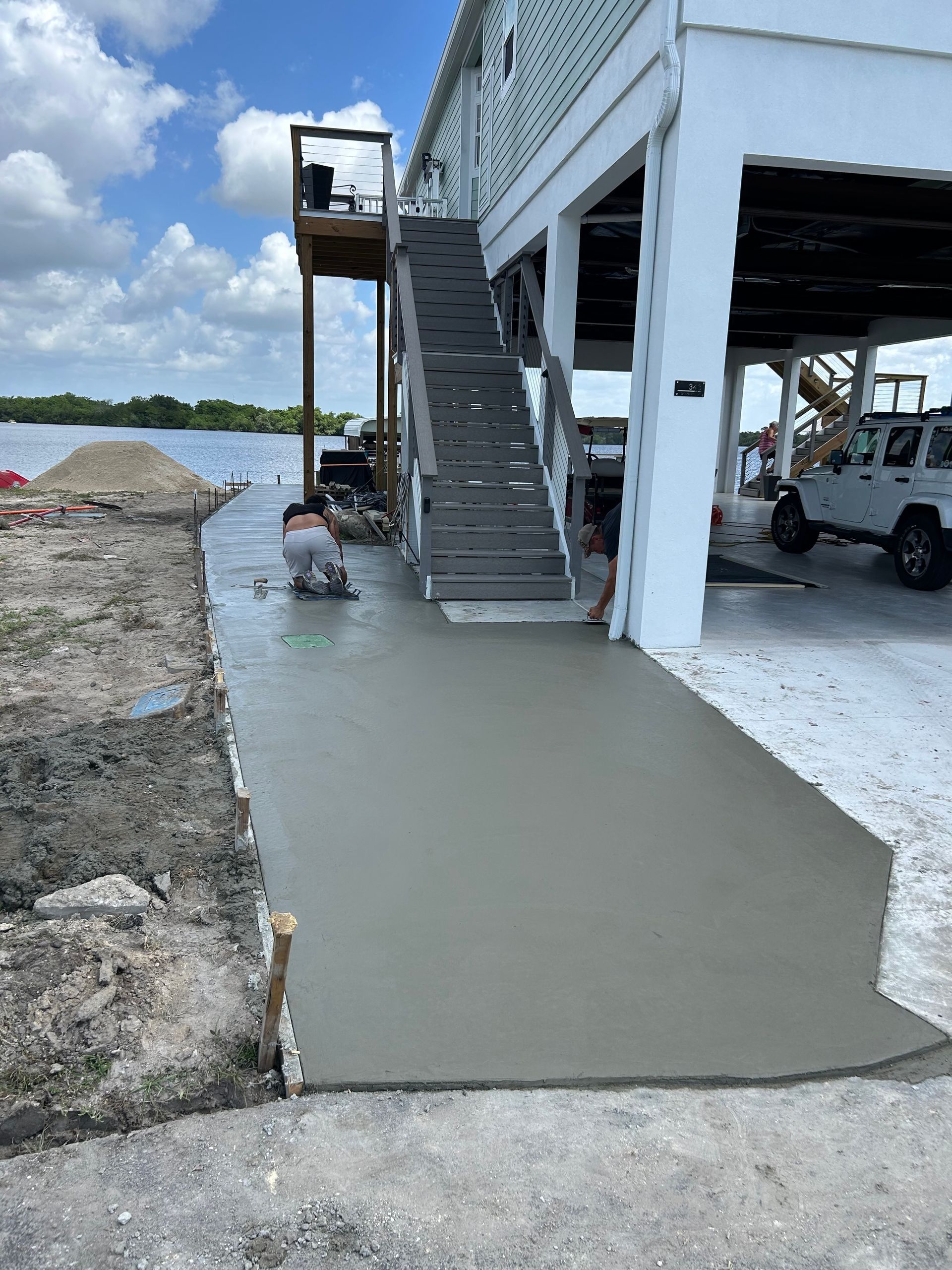 Freshly poured concrete ramp leading to a raised white building by the waterfront