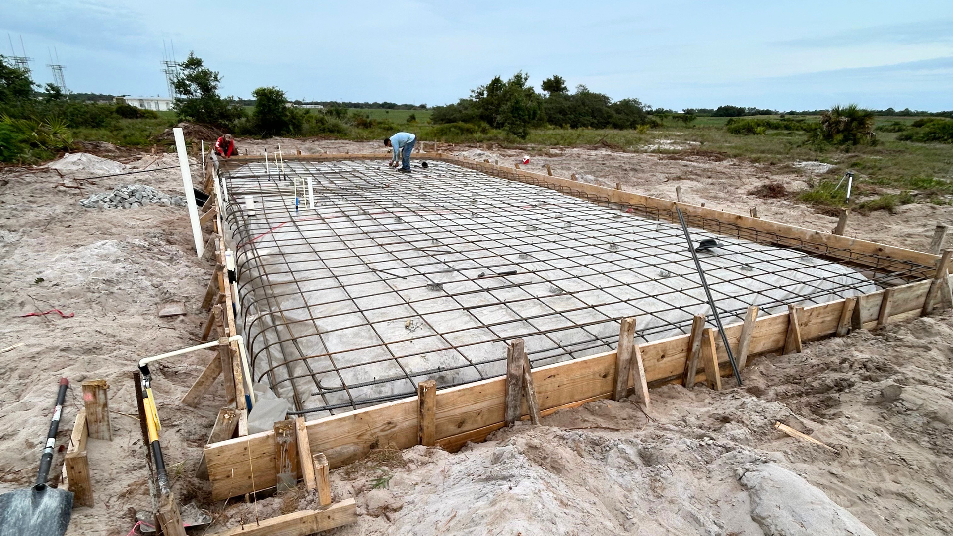 Concrete crew finishing a fresh slab under clear dry season skies in Naples, Florida