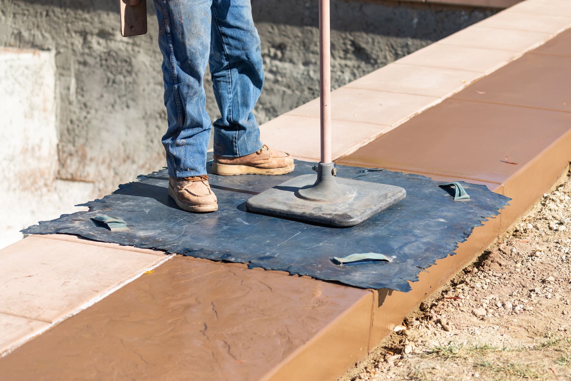A group of men are working on a concrete driveway.